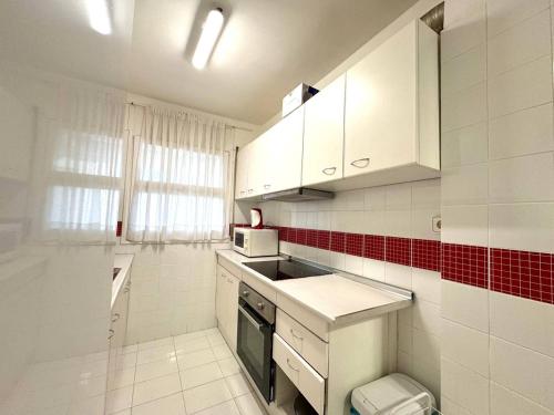 a kitchen with white cabinets and red and white tiles at Apartsalou Blau Mari in Salou