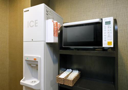 a microwave sitting on a shelf next to a refrigerator at APA Hotel Saitama Higashimatsuyama Ekimae in Matsuyama