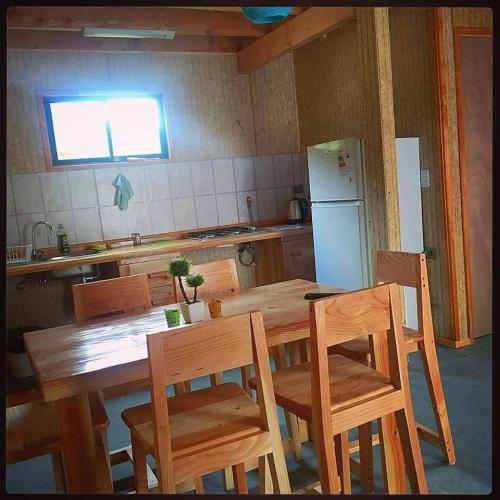 a kitchen with a wooden table and chairs and a refrigerator at Cabañas Mialma Neltume, Huilo Huilo, Accesibles in Panguipulli