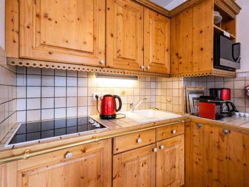 une cuisine avec des placards en bois et un appareil rouge dans l'établissement Résidence Moraine - MORAINE 11 MAE-4441, à Les Allues