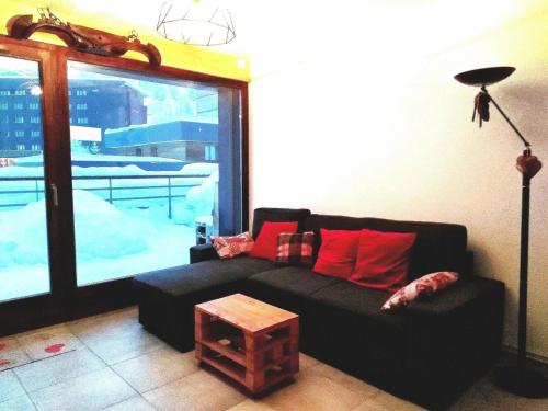 un salon avec un canapé noir avec des coussins rouges dans l'établissement Résidence Lodges 1970 - Résidences LES LODGES 1970 N°B302 MAE-1521, à La Plagne Tarentaise