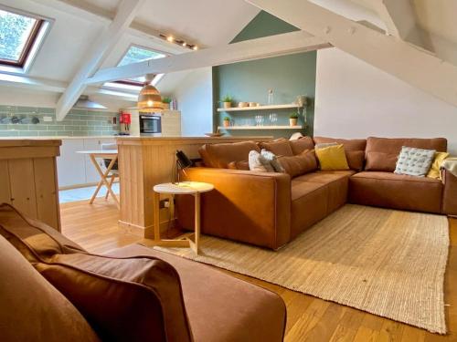 a living room with a brown couch and a kitchen at Stylish & Spacious Town Centre Duplex Apartment in Porthmadog