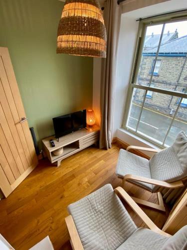 a living room with chairs and a tv and a window at Stylish & Spacious Town Centre Duplex Apartment in Porthmadog