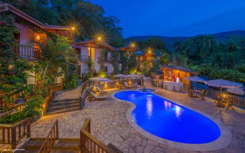 an outdoor swimming pool in a resort at night at Hotel Praia do Portinho in Ilhabela