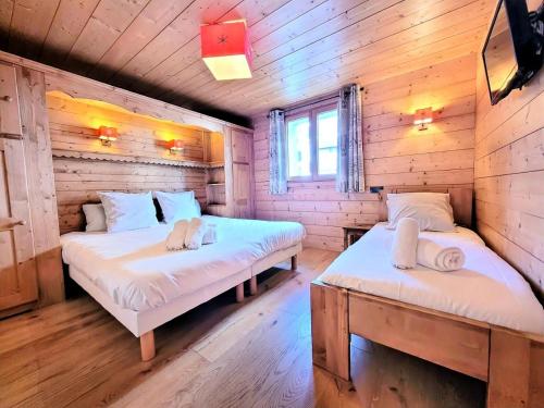 deux lits dans une chambre aux murs en bois dans l'établissement Résidence Epilobe - T3+cabine au coeur du village et proche des pistes MAE-0971, aux Gets