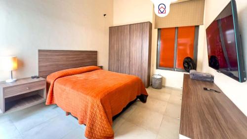 a bedroom with a bed with an orange blanket at Departamento Morelos SLP Centro Historico in San Luis Potosí
