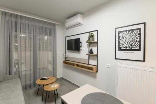 a white living room with a couch and a tv at OMIKRON luxury living in Thessaloniki