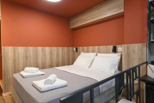 a bed in a room with orange walls and white towels at OMIKRON luxury living in Thessaloniki