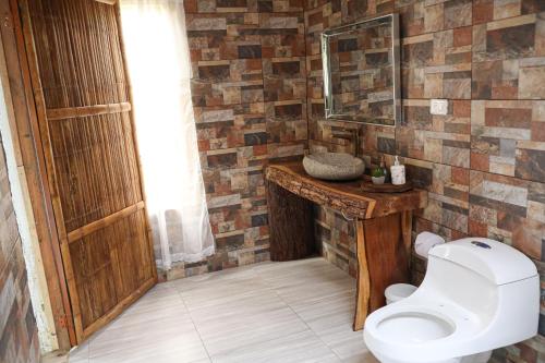 a bathroom with a toilet and a stone wall at Alojamiento rural Ecoparque La Motilona Paicol, Huila - Cabaña Colibrí in Paicol