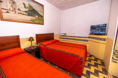a room with two beds and a couch and a television at Hotel La Sin Ventura in Antigua Guatemala