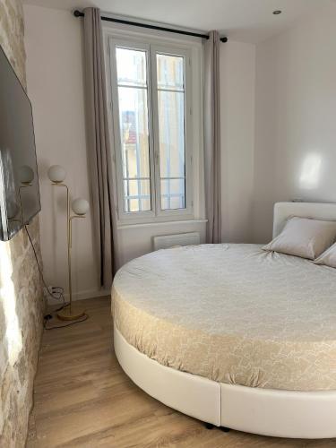 a white bedroom with a large bed in front of a window at Paris Secret Spot - Loft Unique aux portes de Paris in Gentilly