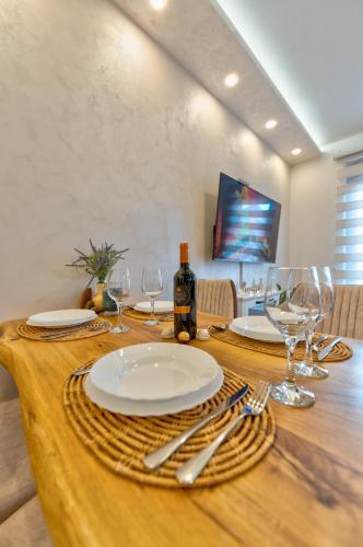 a wooden table with plates and wine glasses on it at Apartman Andjela12 Zlatibor in Ocka Gora