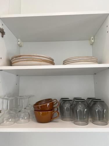 a shelf with bowls and plates and a cup at Paris Secret Spot - Loft Unique aux portes de Paris in Gentilly