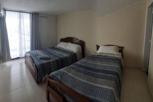 two beds in a small room with a window at Apto vista al mar en playa Rodadero in Santa Marta