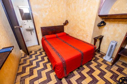 a red bed in a room with a bathroom at Hotel La Sin Ventura in Antigua Guatemala