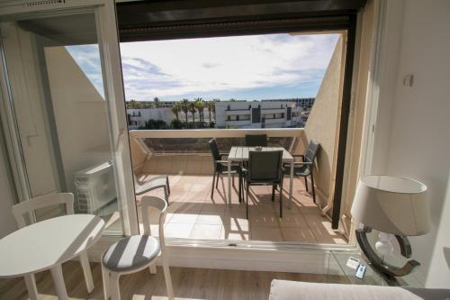 une chambre avec un balcon avec une table et des chaises dans l'établissement CAP D'AGDE Naturiste Heliopolis - PLUME, au Cap d'Agde