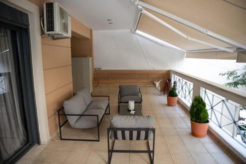 a balcony with two chairs and a couch and a table at Υπέροχο διαμέρισμα με πάρκινγκ in Larisa