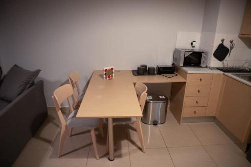 a kitchen with a wooden table with chairs and a microwave at Υπέροχο διαμέρισμα με πάρκινγκ in Larisa