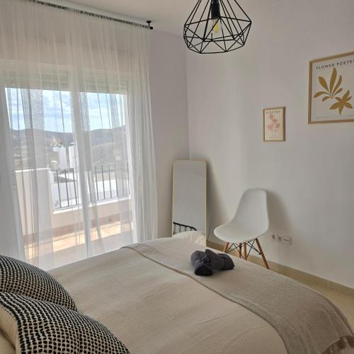 a bedroom with a bed and a chair and a window at Casa Serena Alojamiento Rural in Enix