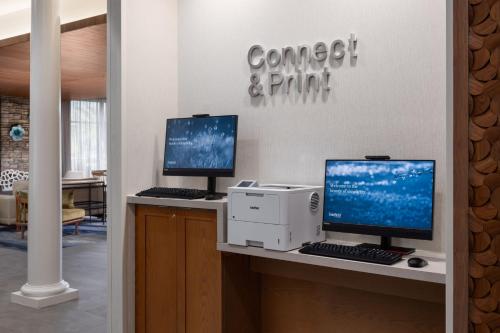 two computer monitors and a printer on a desk at Fairfield by Marriott Inn & Suites Waycross in Waycross
