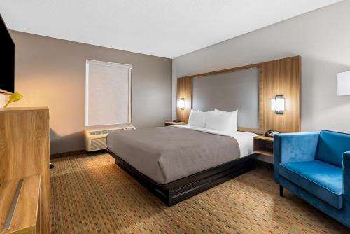 a hotel room with a bed and a blue chair at Quality Inn in Cornelia