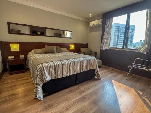 a bedroom with a bed and a large window at Flat Hotel Executivo em Congonhas in Sao Paulo