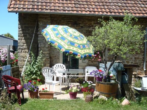 a patio with a table and chairs and an umbrella at La maison du Gué in Écutigny