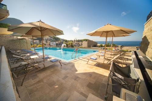 a swimming pool with chairs and umbrellas at Exclusive Hotel in Budva
