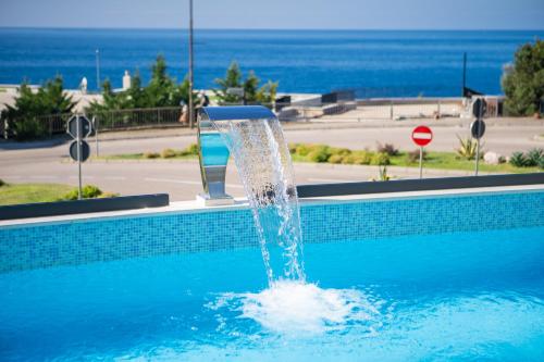 a fountain in a swimming pool with a view of the ocean at Exclusive Hotel in Budva