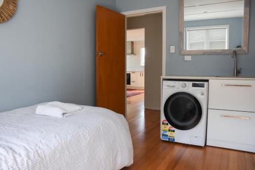 a bedroom with a bed and a washing machine at Beautiful home with short stroll to Havelock Village in Havelock North