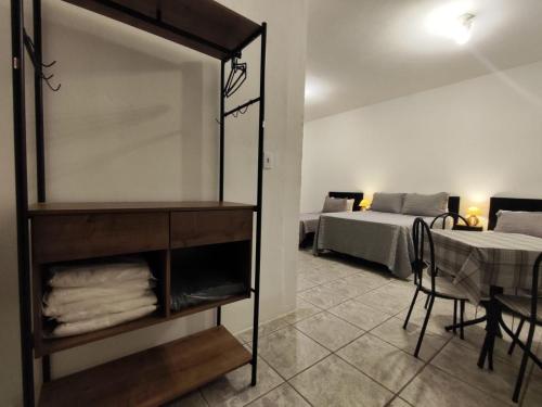 a room with a bed and a shelf with towels at Villa Bilac - Amplos Studios 2km da Vila Germânica in Blumenau