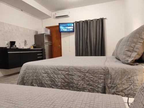a bedroom with a bed and a tv on the wall at Villa Bilac - Amplos Studios 2km da Vila Germânica in Blumenau