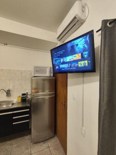 a tv on the wall of a kitchen with a refrigerator at Villa Bilac - Amplos Studios 2km da Vila Germânica in Blumenau