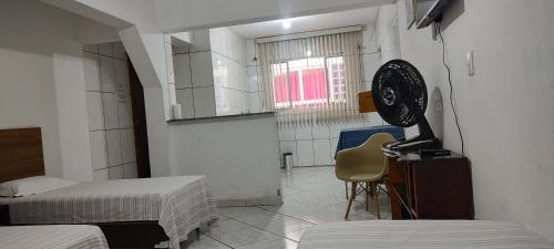 a room with two beds and a fan on a table at Pousada Guarulhos in Guarulhos