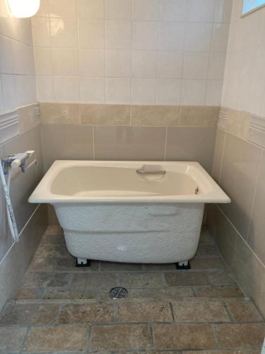 a bath tub in a bathroom with a tiled floor at Haryugetu Guesthouse in NASA in Kaiyo