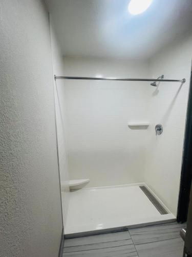 a white shower in a bathroom with a white wall at BlissPoint Inn, Kokomo in Kokomo