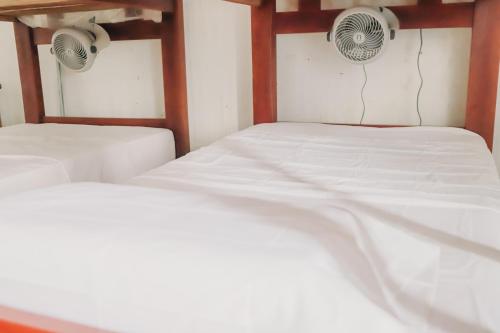 two beds in a room with white sheets at Hostal Casa en la Ciénaga Rincon del Mar in Rincón