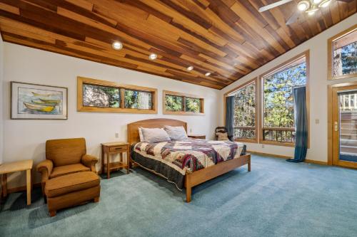 a bedroom with a bed and a chair and windows at New! Birch Fairway House - On golf course - Hot tub - Garage - Family friendly in McCall