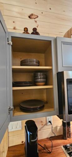 a cabinet with plates and dishes in it at Lot 7 Tiny Home on the River in Cosby