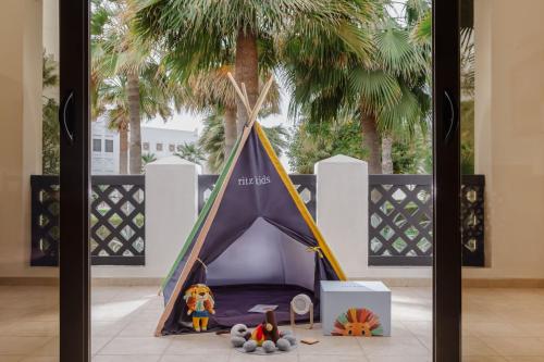 a tent with toys in front of a palm tree at Sharq Village & Spa, a Ritz-Carlton Hotel in Doha