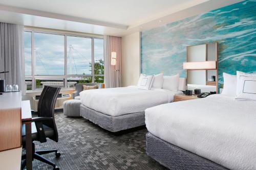 a hotel room with two beds and a desk at Courtyard by Marriott Erie Bayfront in Erie