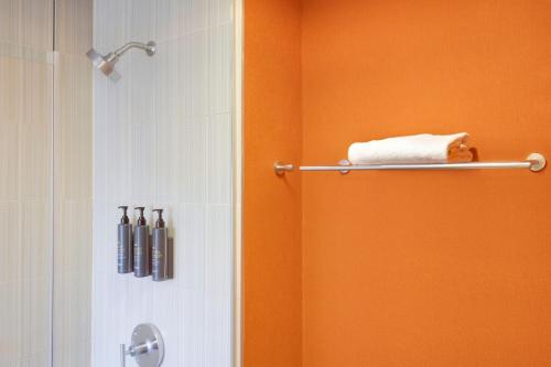 an orange bathroom with a shower and a towel at aloft Hotel Milwaukee Downtown in Milwaukee