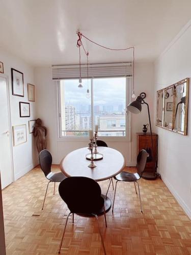 une salle à manger avec une table et des chaises et une fenêtre dans l'établissement Vaste appt baigné de lumière, à Paris