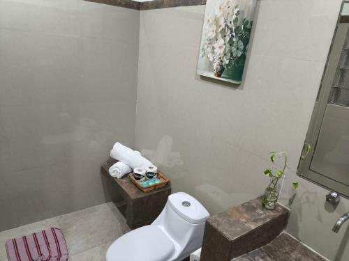 een badkamer met een toilet en een vaas met bloemen bij La casa de Luna in Puerto Vallarta