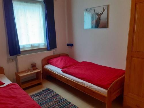 a bedroom with a bed with red sheets and a window at holiday village Bad Hundertpfund in Großbreitenbach