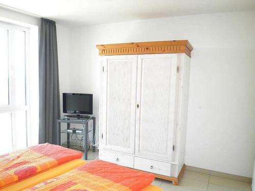 a bedroom with a white cabinet and a television at Kniepsand in the Amrumer Welle in Wittdün