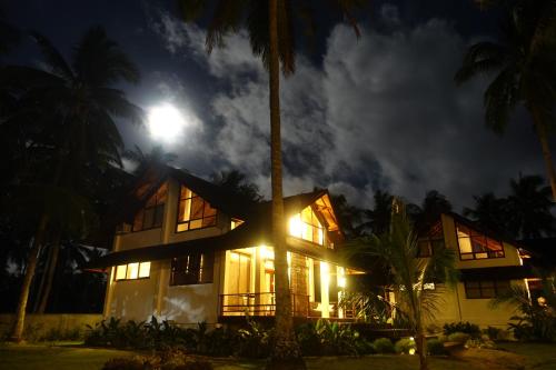 a house at night with the moon behind it at Sandy Feet Siargao in General Luna