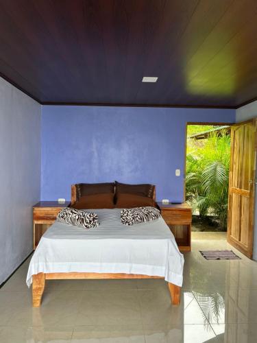 a bedroom with a bed with a blue wall at Encanto Arenal lodge in Fortuna