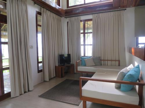 a living room with a couch and some windows at Sandy Feet Siargao in General Luna