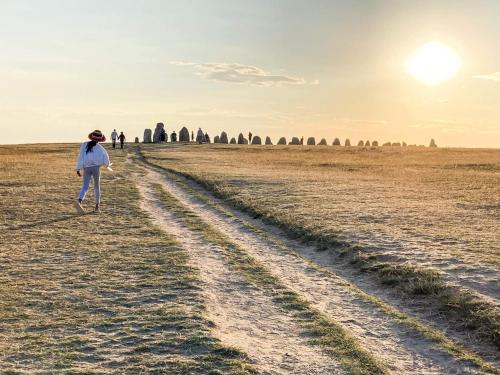 a woman walking in a field with the sun in the background at 5 star holiday home in SIMRISHAMN in Simrishamn